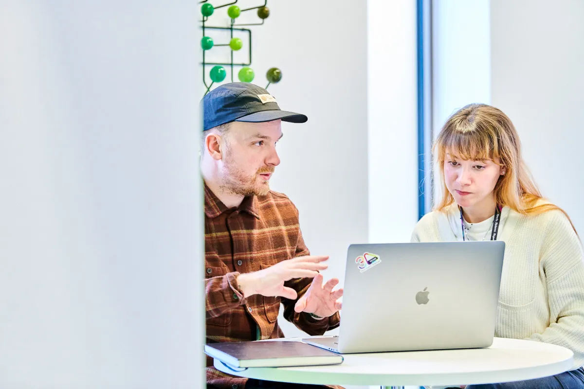 Leighton colleagues sat talking, working on a laptop. 