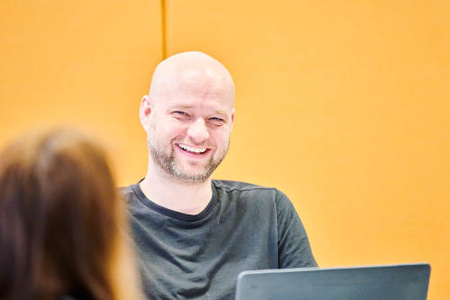 Senior front-end engineer, Chris McGreevy laughing, whilst working in an office setting. 