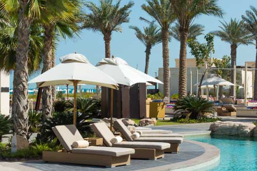 Empty hotel sun loungers next to a swimming pool. 