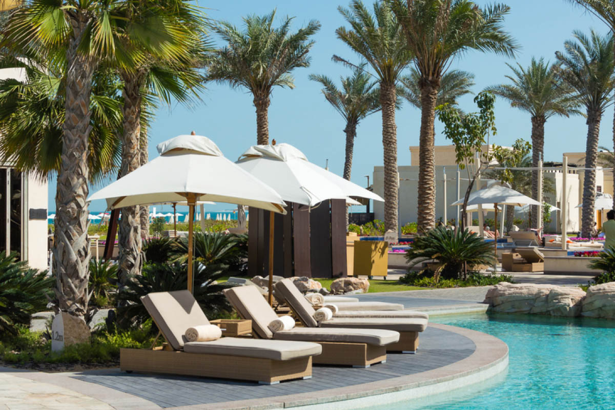 Empty hotel sun loungers next to a swimming pool. 