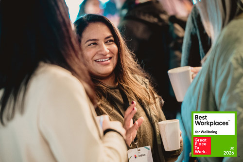A Leighton colleague smiling, overlaid with the Best Workplaces for Wellbeing badge. 