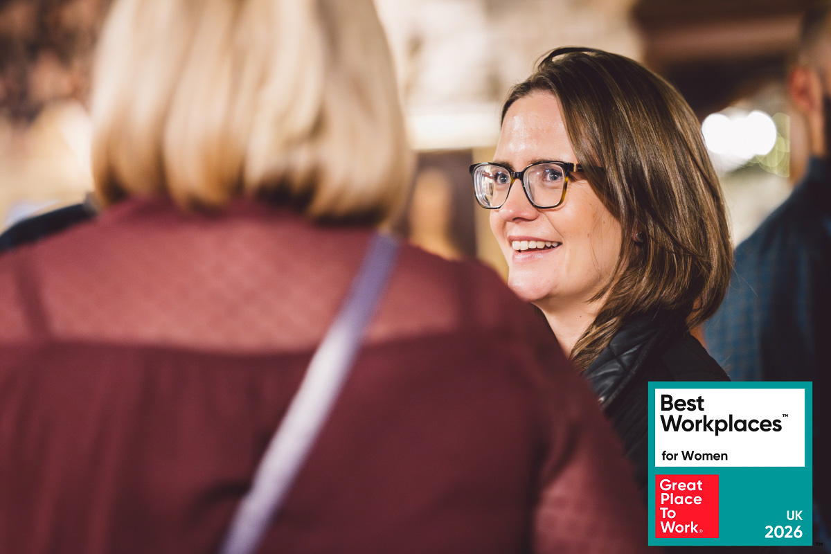 Two Leighton colleagues stood, chatting to one another with the Great Place to Work badge overlaid.