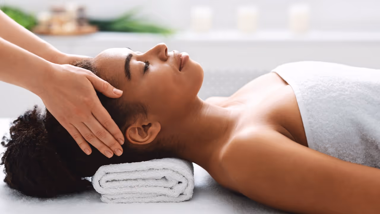 A woman lying on her back having her head rubbed gently