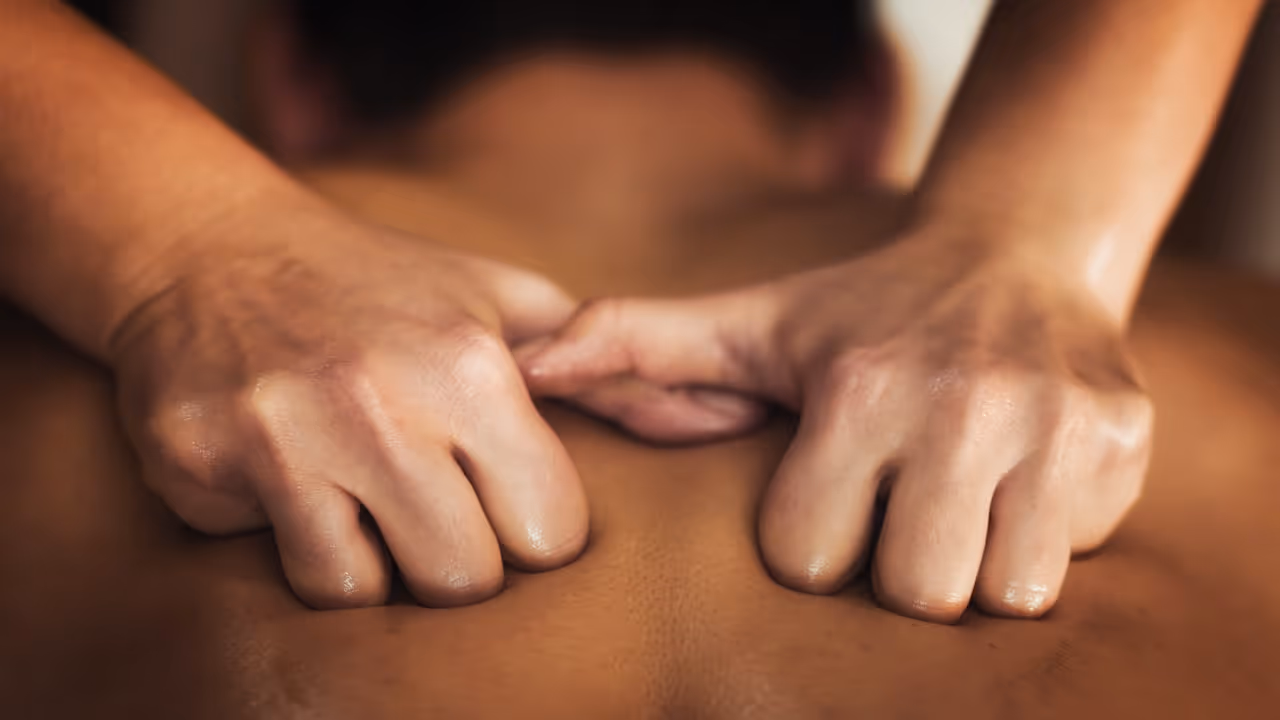 Closeup of hands massaging the upper half of a back