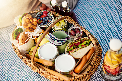 subs, dips, fresh pretzels and blueberries, strawberries in a nice picnic basket