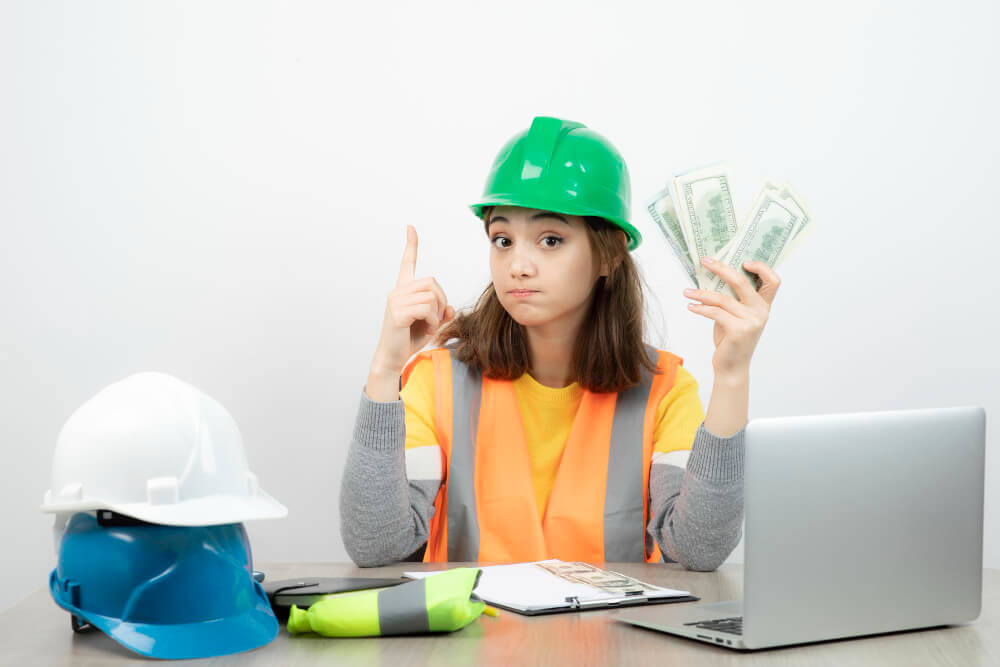 Ein Bauarbeiter mit grüner Schutzhelm und Sicherheitsweste zeigt auf Geldscheine – Symbolbild für Kosten in der Industriemeister-Ausbildung.