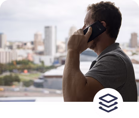 Side view of a man talking on a smartphone with a blurred cityscape in the background.