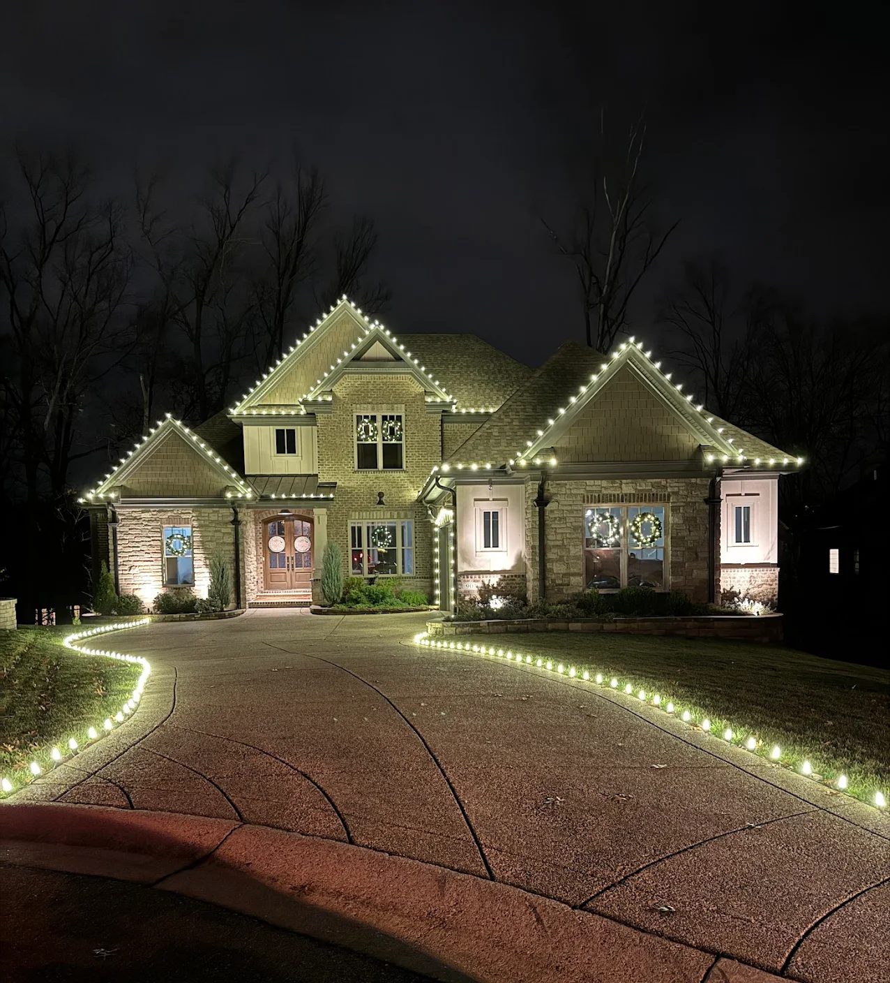 Home lit with warm white roofline and driveway lights