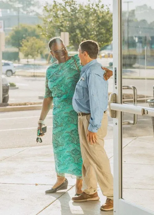 Two church members warmly greeting each other at the entrance of Southeast Christian Church.