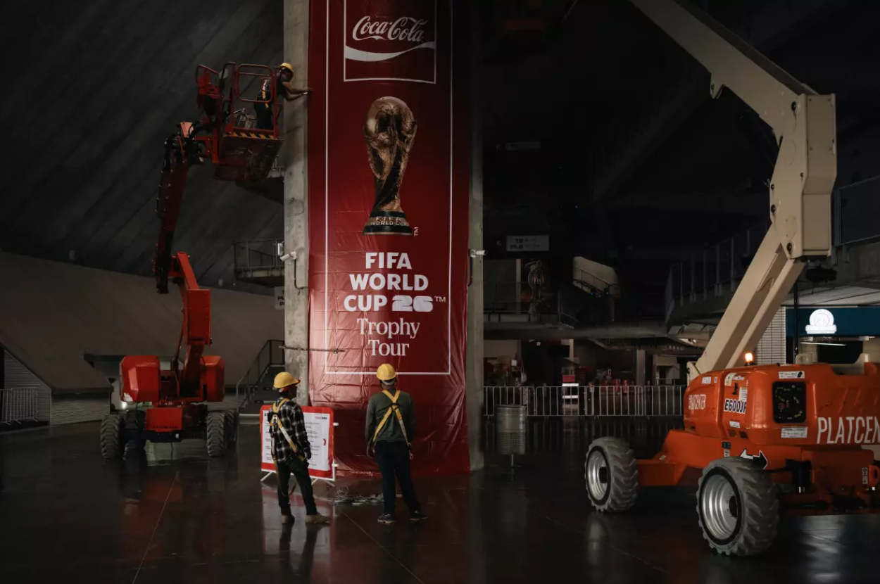 Workers install a World Cup 2026 sign inside Akron Stadium, just outside Guadalajara, where four World Cup games will be held. Guadalajara and surrounding cities have been sprucing up for the world’s premier soccer tournament. (Felix Marquez / For The Times)