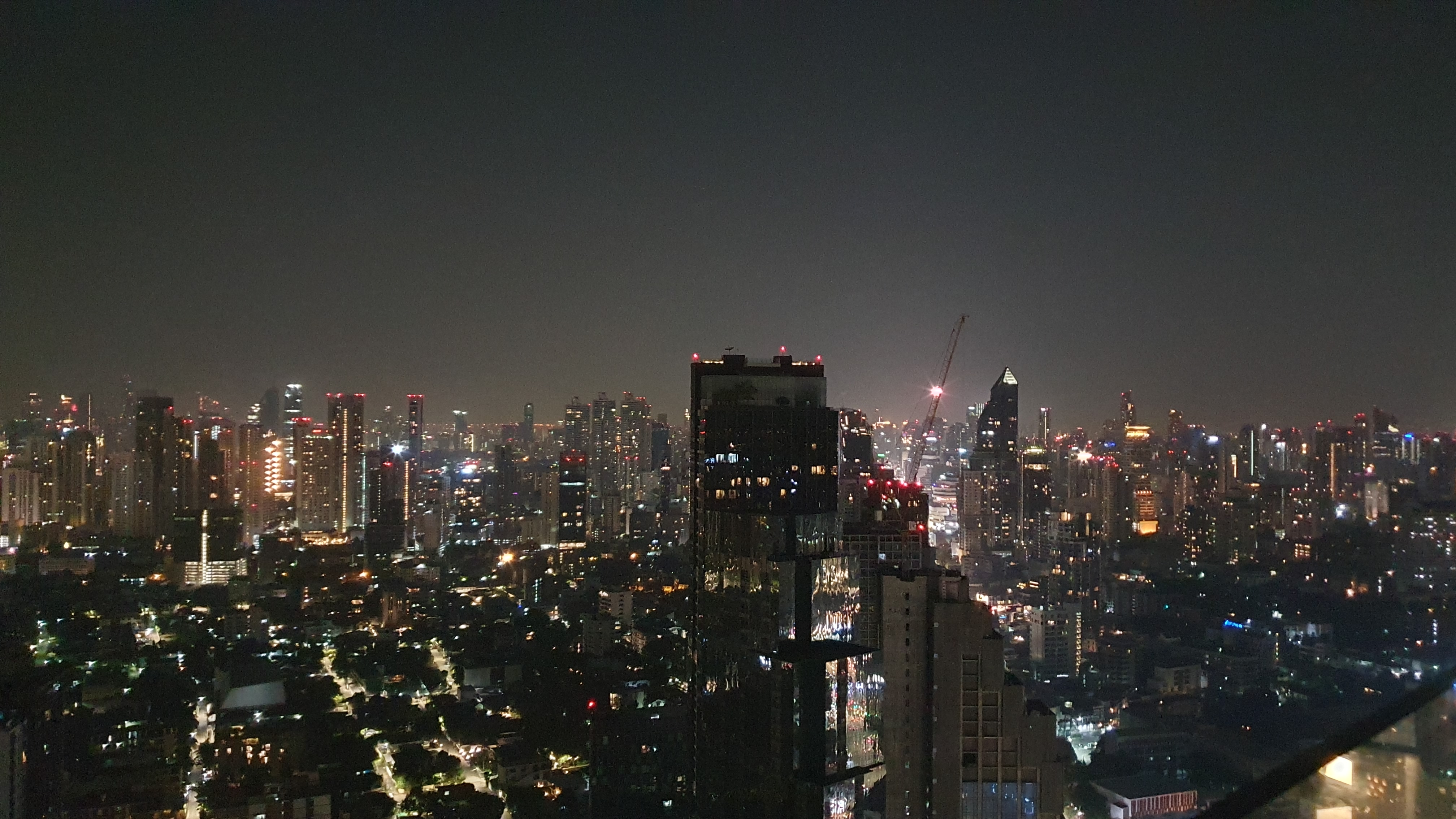 Nighttime city skyline with numerous illuminated skyscrapers and buildings under a clear dark sky.