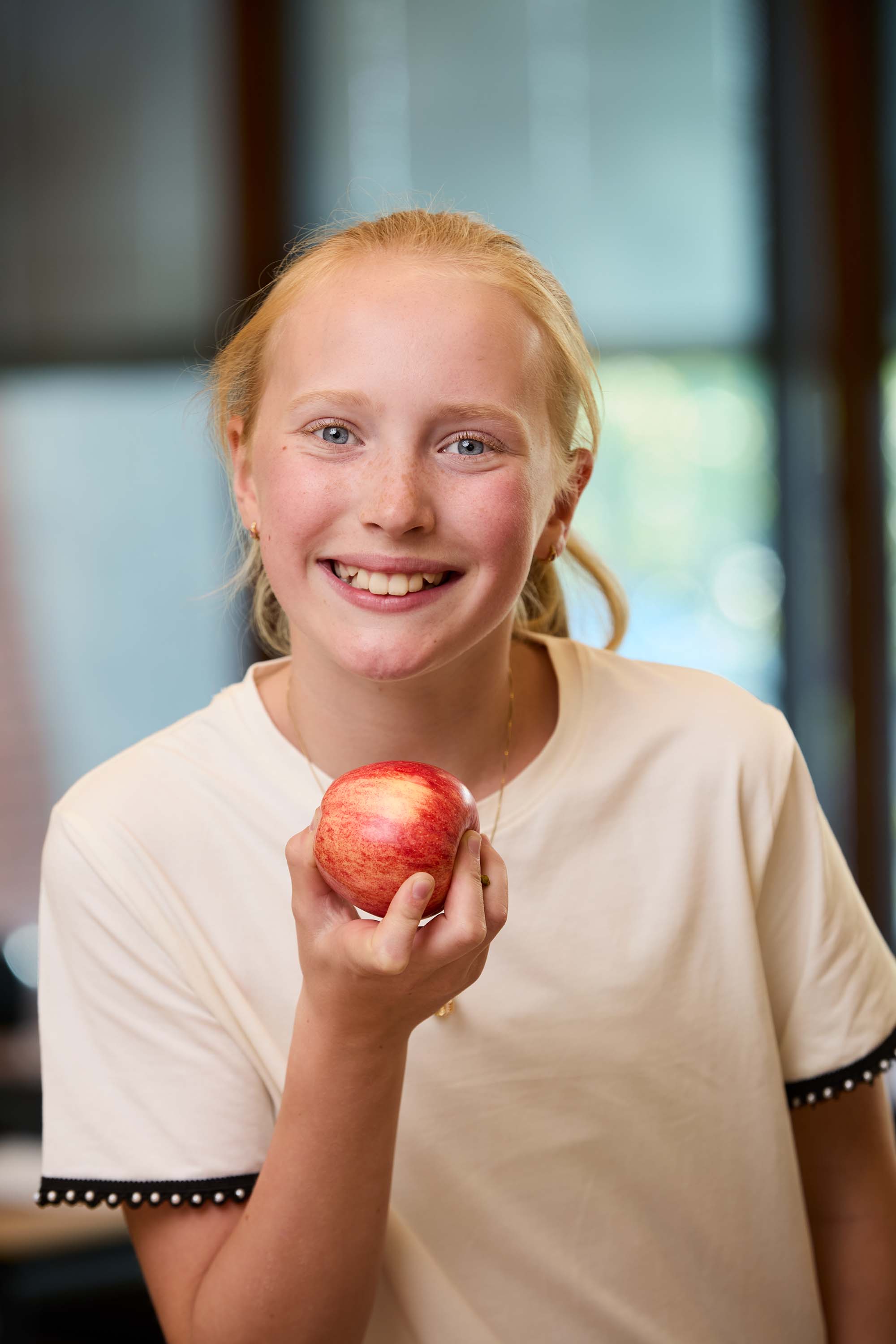 Bilde av en elev som smiler og holder et rødt eple