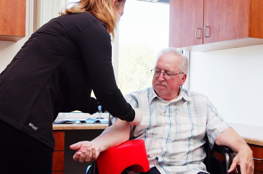 Older man getting an IV put in with arm rested on The Heart
