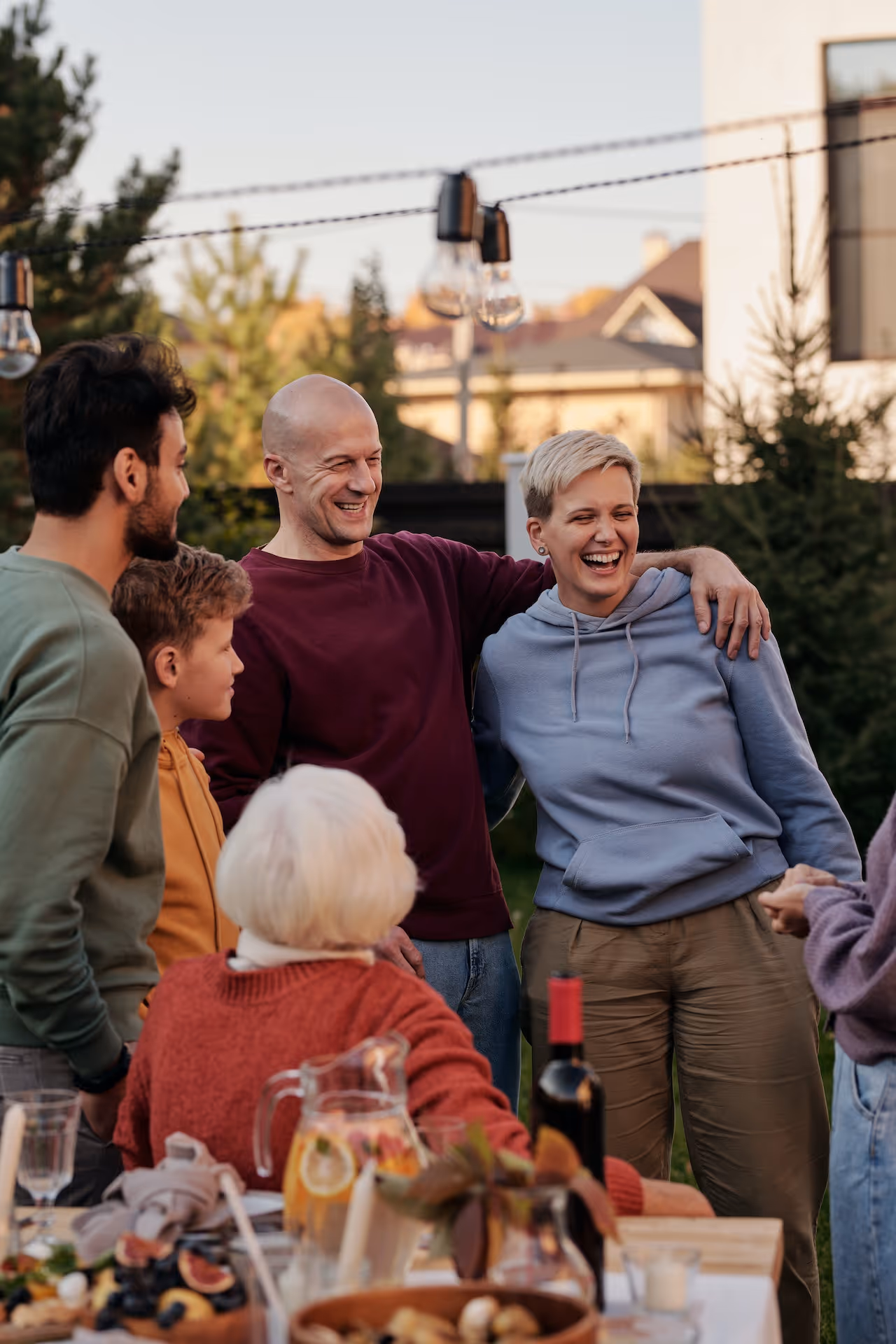 family_laughing_in_backyard_bald_man_red_sweater_short_haired_female_light_blue_sweater