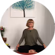 woman_with_short_blonde_hair_smiling_sitting_down_cross_legged_yoga_style_with_olive_green_shirt_google_review_image_deeded