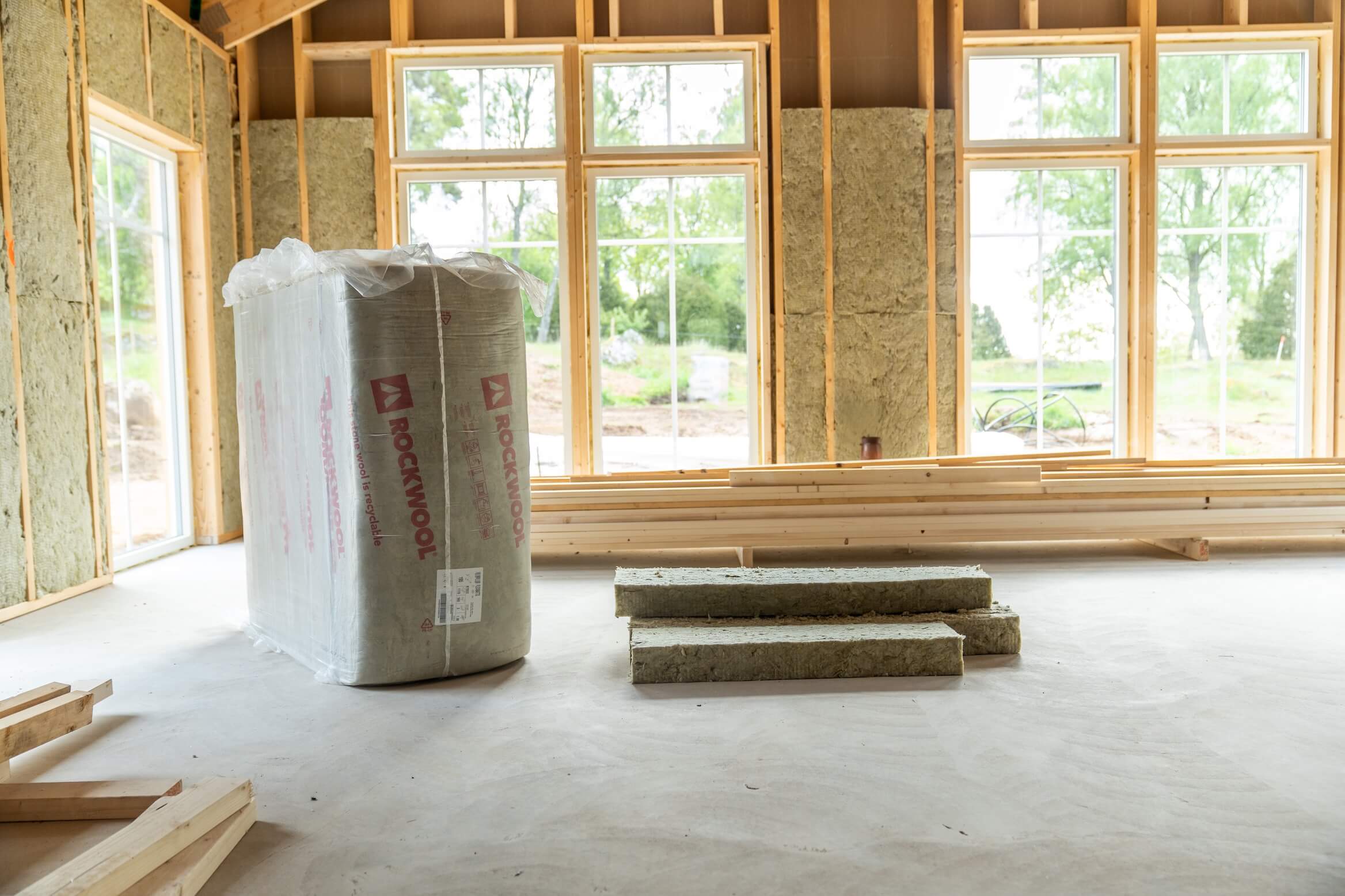 Nybyggt trähus med emballerad ROCKWOOL stenullsisolering och isolerskivor redo att installeras