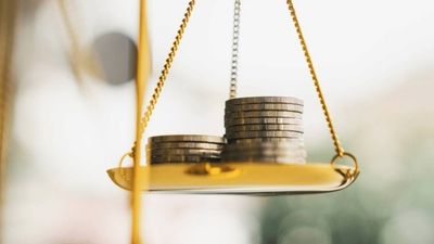 Coins piled up on a hanging scale.