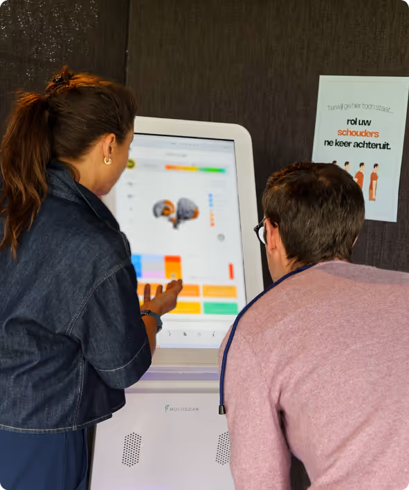 Twee mensen bediscussiëren een medische scan op een groot touchscreen van een medische kiosk.