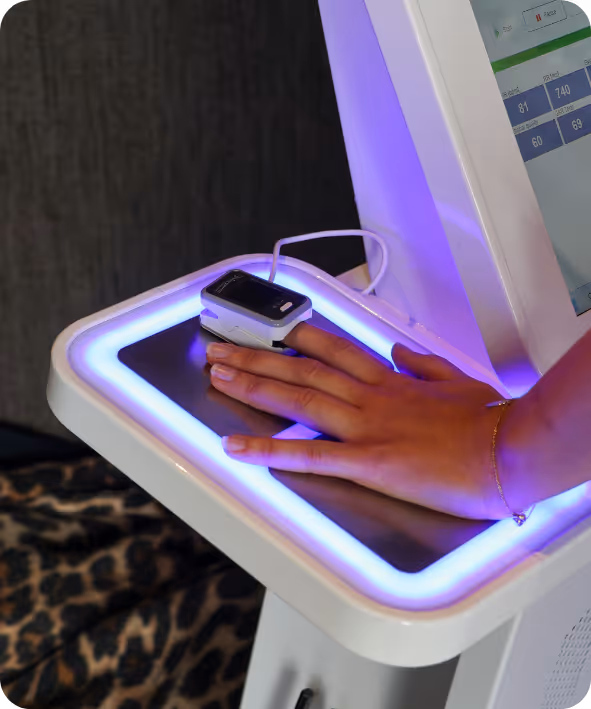 Hand with a pulse oximeter on the finger placed on a glowing platform of a medical device.