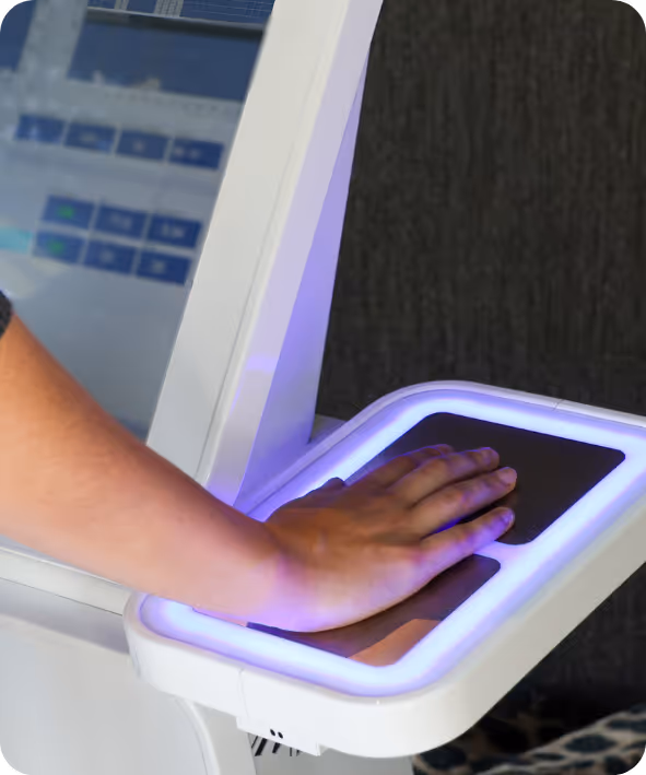 Hand placed on a biometric scanner pad with blue light on a white device.