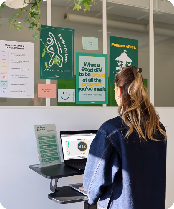 Vrouw werkt op laptop aan bureau met motiverende posters aan raam op kantoor.