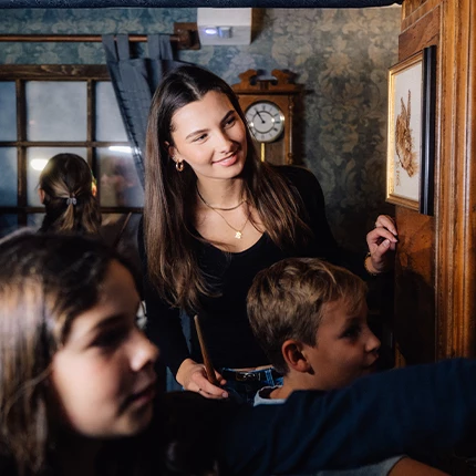 „Eine lachende Familie löst gemeinsam ein Rätsel in einem detailreich gestalteten Escape Room.“
