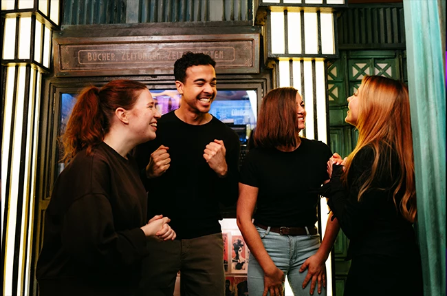 Begeisterte Schulklasse beim Wandertag in Berlin vor dem Eingang von EXIT Berlin im Admiralspalast für ein gemeinsames Escape-Game-Abenteuer.