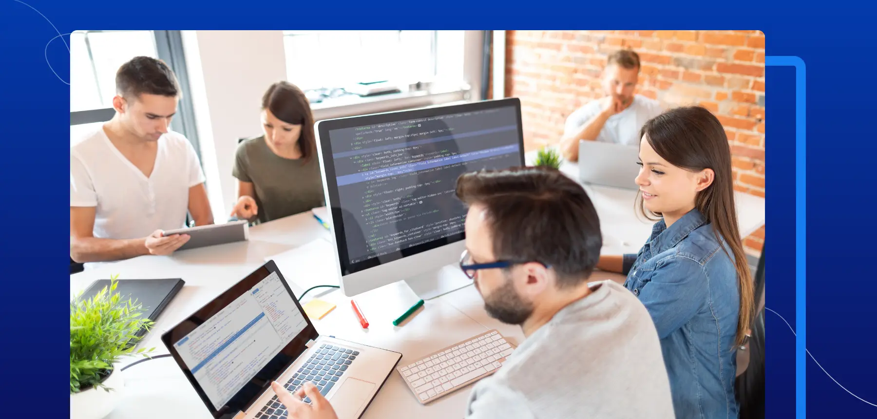 Developers collaborating in a modern office, reviewing code on laptops and monitors while integrating eSignature workflows using Blueink API.