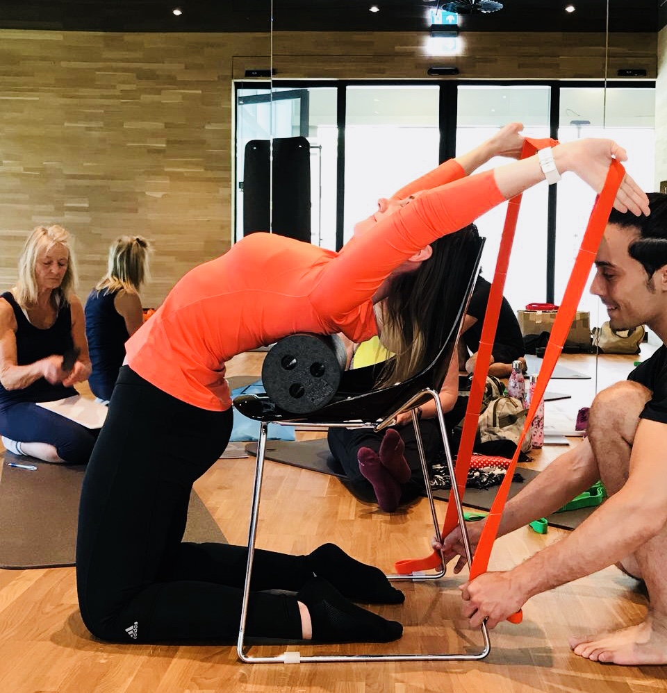 Allieva in esercizio di Biokinematik con elastici rossi, flessione in avanti del busto