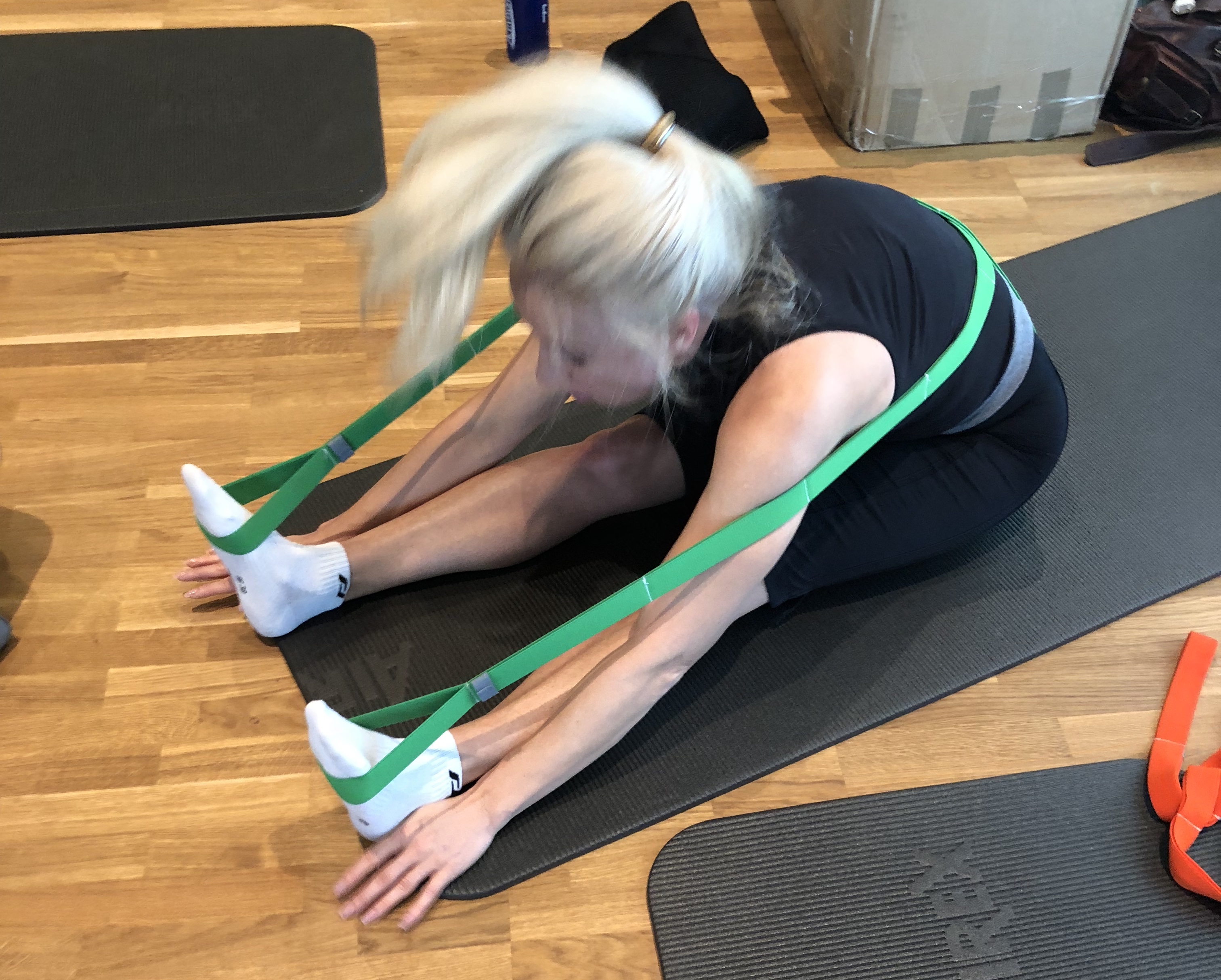 Allieva a terra con elastici verdi, esercizio di Biokinematik per l’allungamento delle gambe