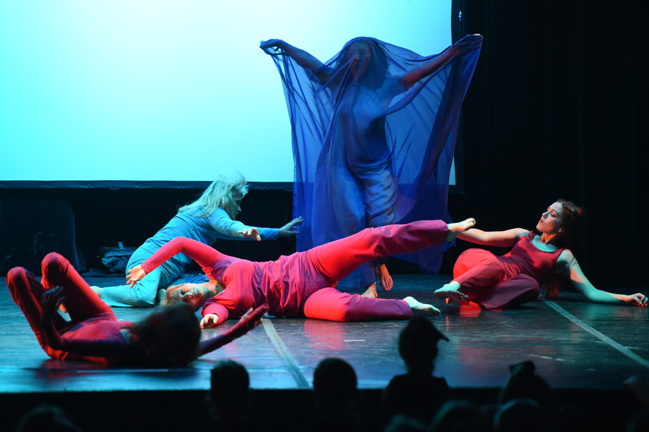 Performance Oggidanza con tessuto blu come scenografia e danzatrici sdraiate.