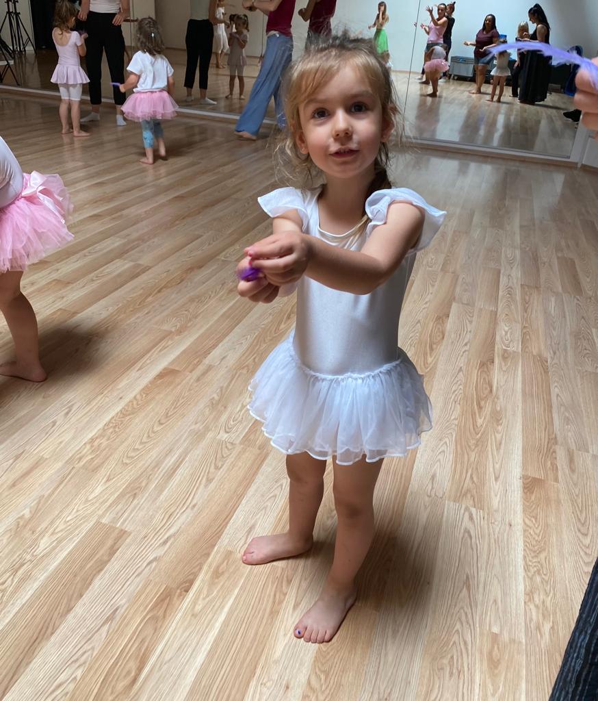 Allieva in costume rosa posa sorridente in sala danza