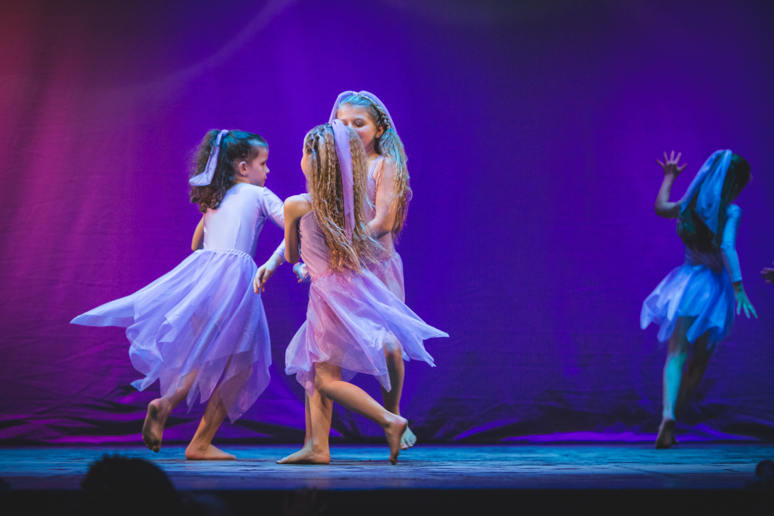 Gruppo di allieve in costumi lilla eseguono coreografia sul palcoscenico