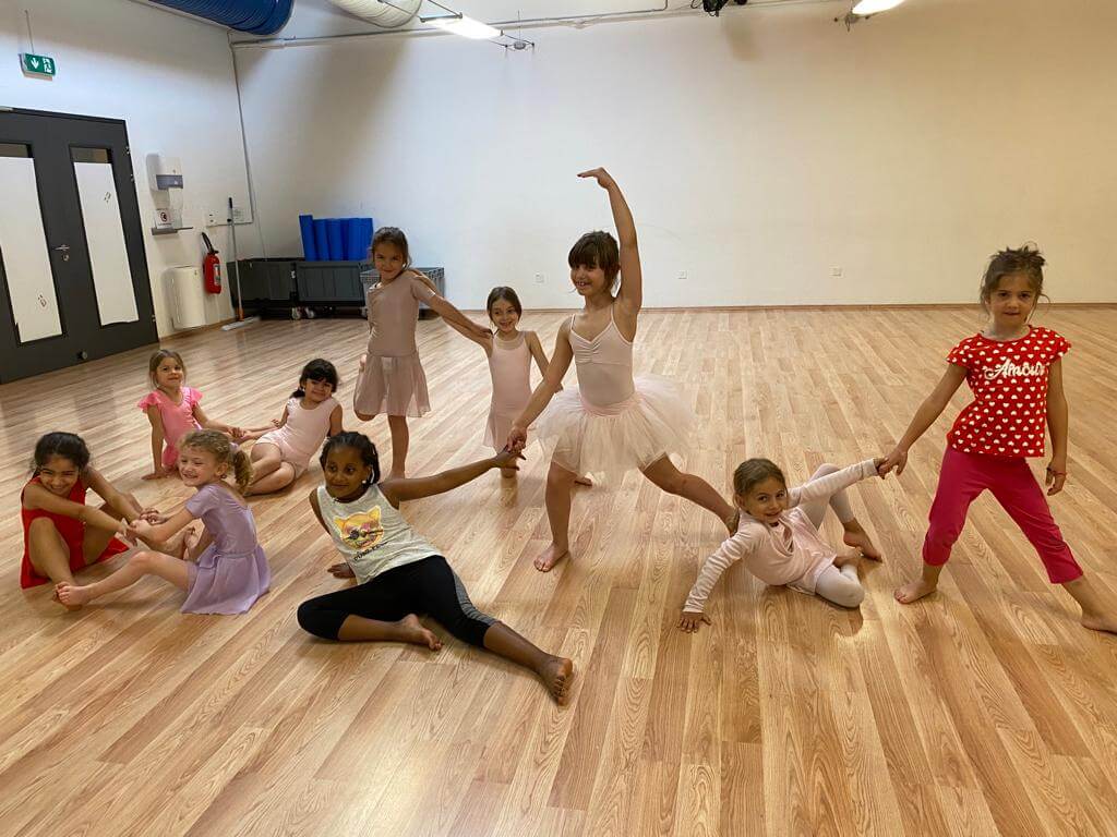 Classe di bambine in sala danza durante esercizi a terra