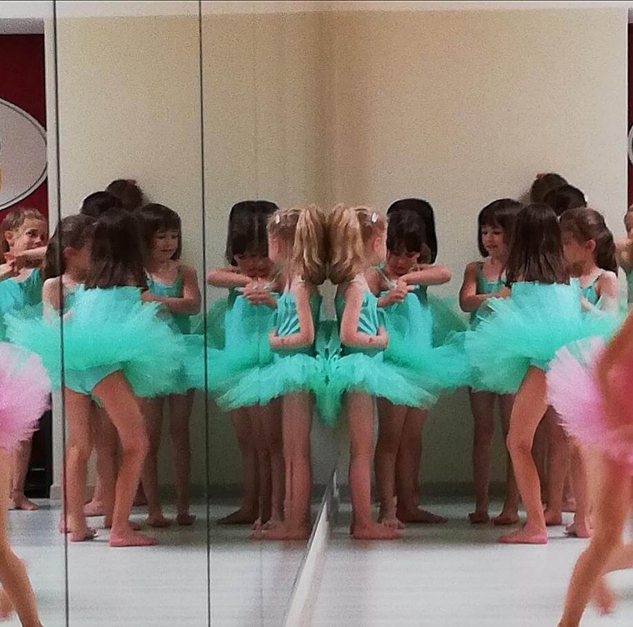 Gruppo di bambine in abiti turchesi davanti allo specchio in sala danza