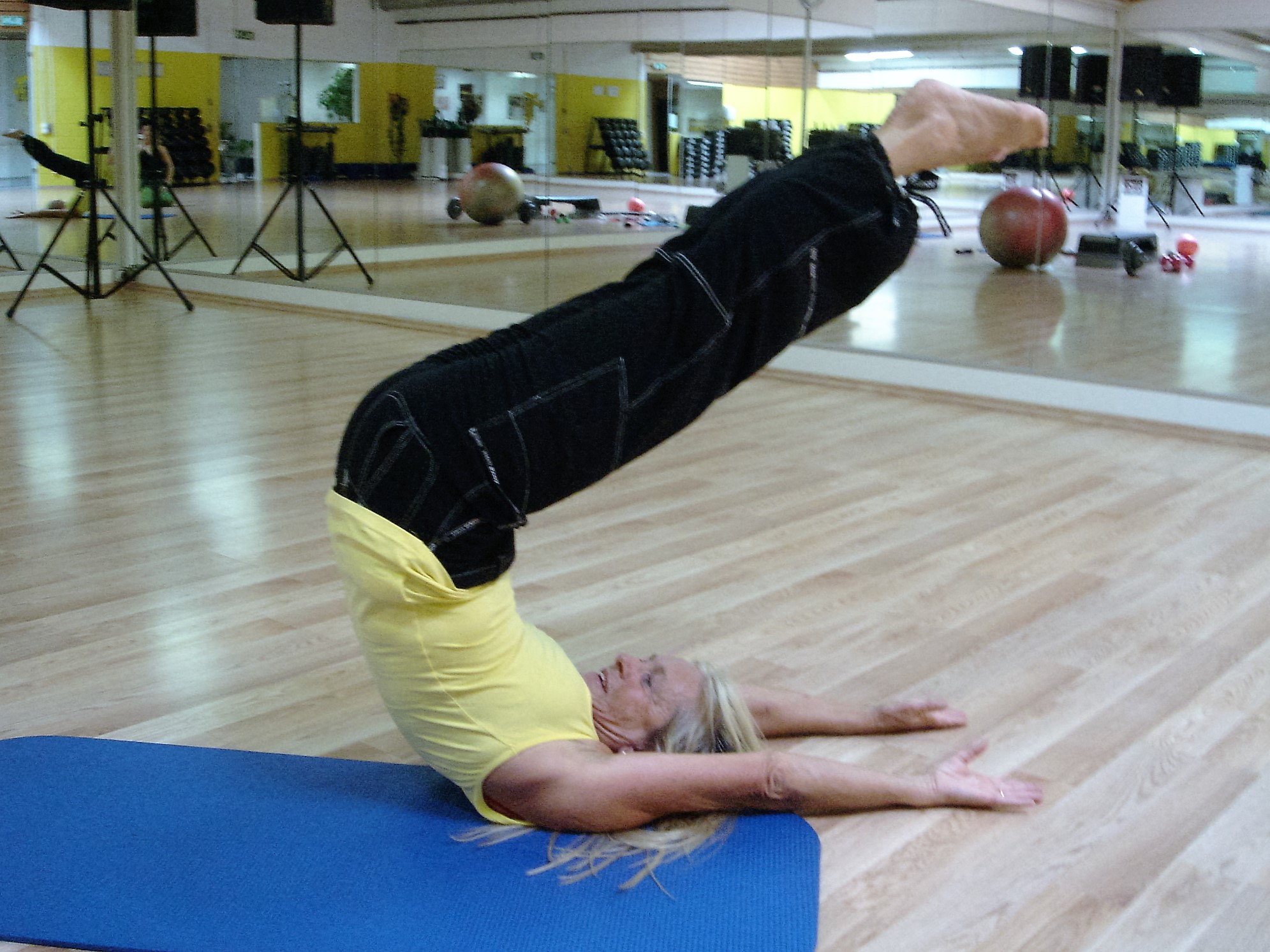 Esercizio Yoga con gambe allungate oltre la testa su tappetino