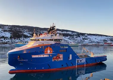 A blue anchor handling tug supply (AHTS) vessel in a bay in winter time.