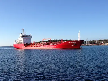 Bright-red cargo vessel SILVER MARY (home port Bergen) under way in a Norwegian fjord, with deck cranes and containers visible against a backdrop of mountains and coastal town.