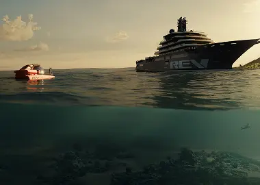 Split-level ocean scene at sunset showing a large yacht marked “REV” on the surface with a small red submersible nearby, and an underwater view of reef and open water below.