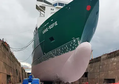 The green-hulled vessel Anne-Sofie positioned in dry dock, showing its bow and pale lower hull.