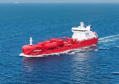 Aerial view of the red chemical tanker HAVSTRAUM sailing across open blue water, leaving a white wake behind it.