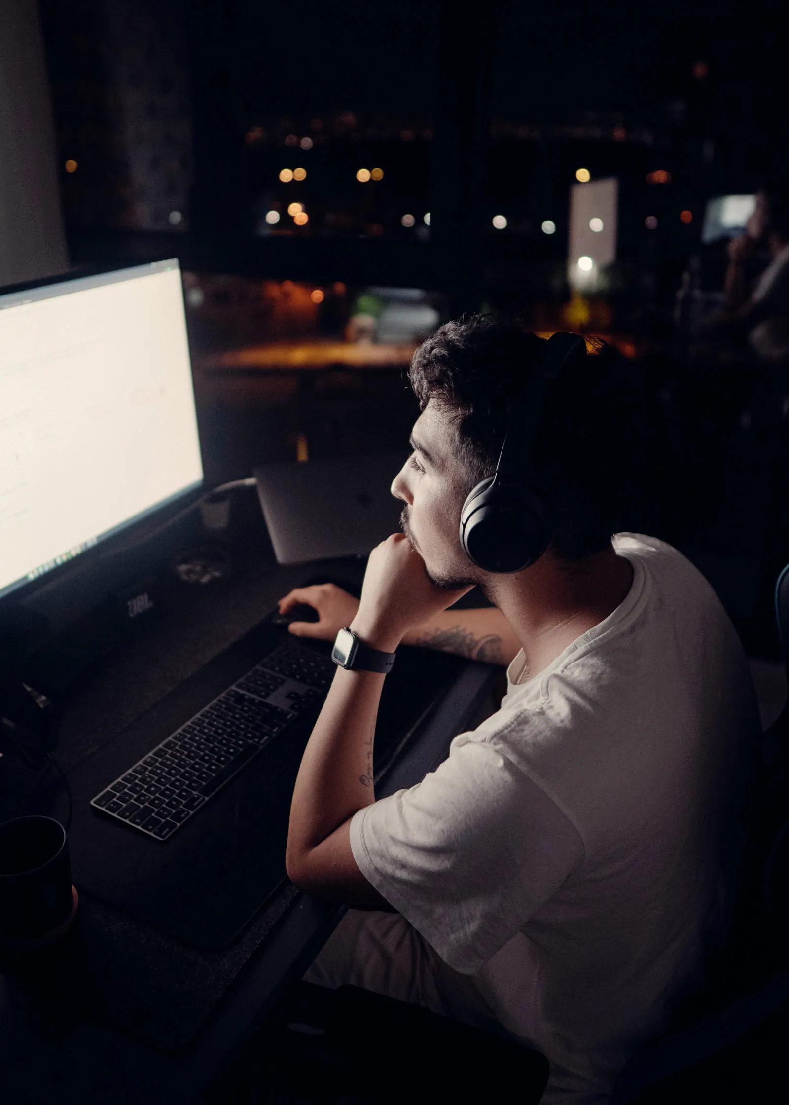 Man with headphones on computer in dark room