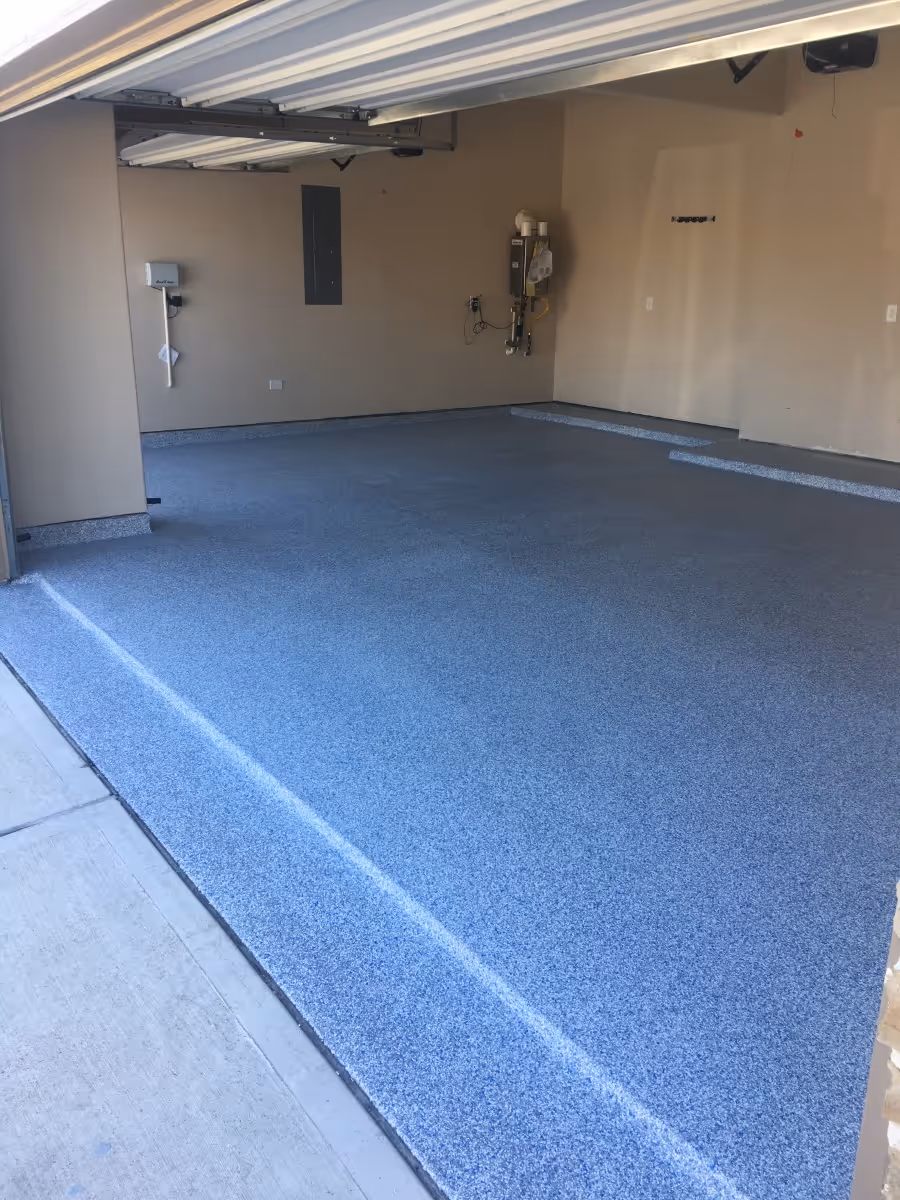 Empty garage with newly installed blue and gray speckled epoxy flake flooring.