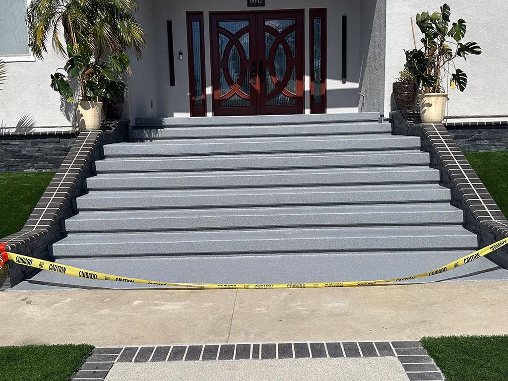 Front entrance with wide gray steps bordered by dark brick railings and caution tape across the bottom step.