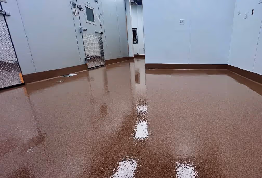 Room with clean, shiny brown quartz epoxy flooring and white walls with metal door panels.