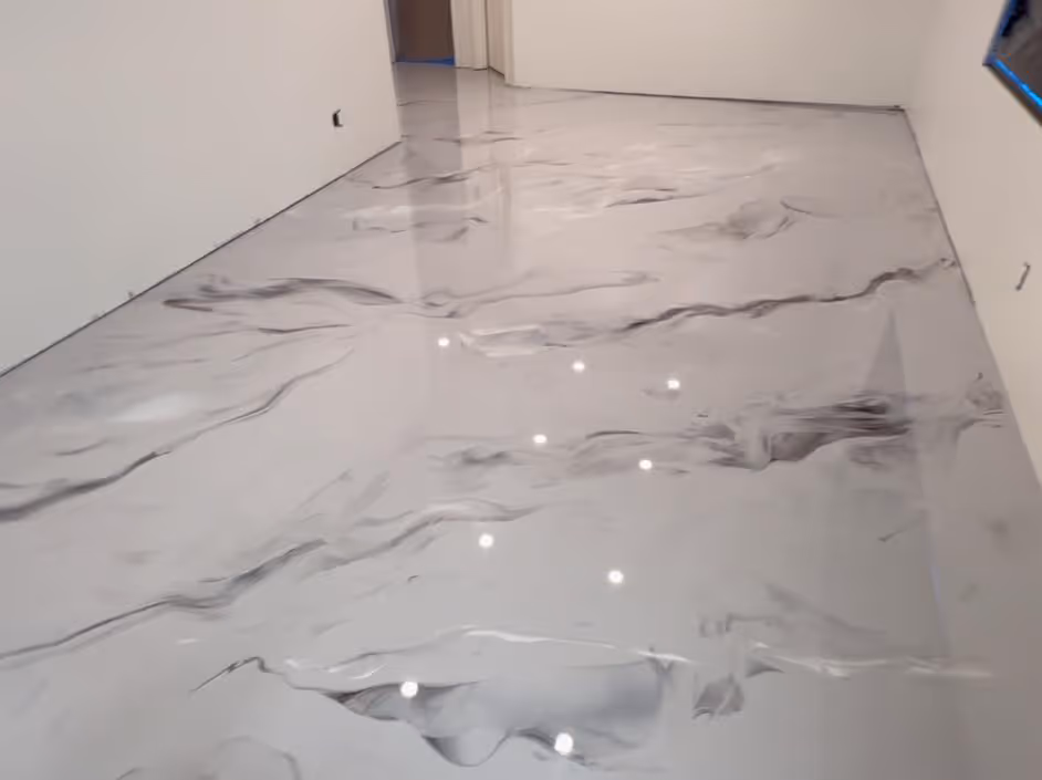 Room with freshly installed metallic epoxy floor featuring a smooth, glossy surface with swirling gray patterns on a light background.