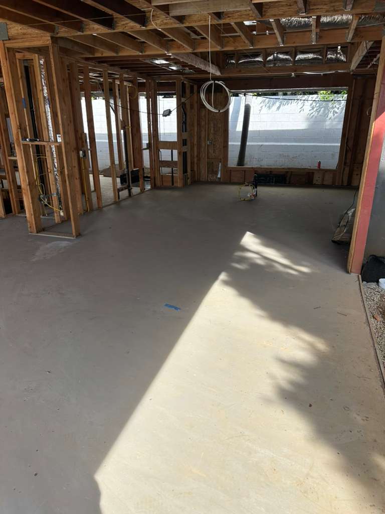 Interior view of a room under construction with wooden framing and a smooth, newly poured concrete floor.