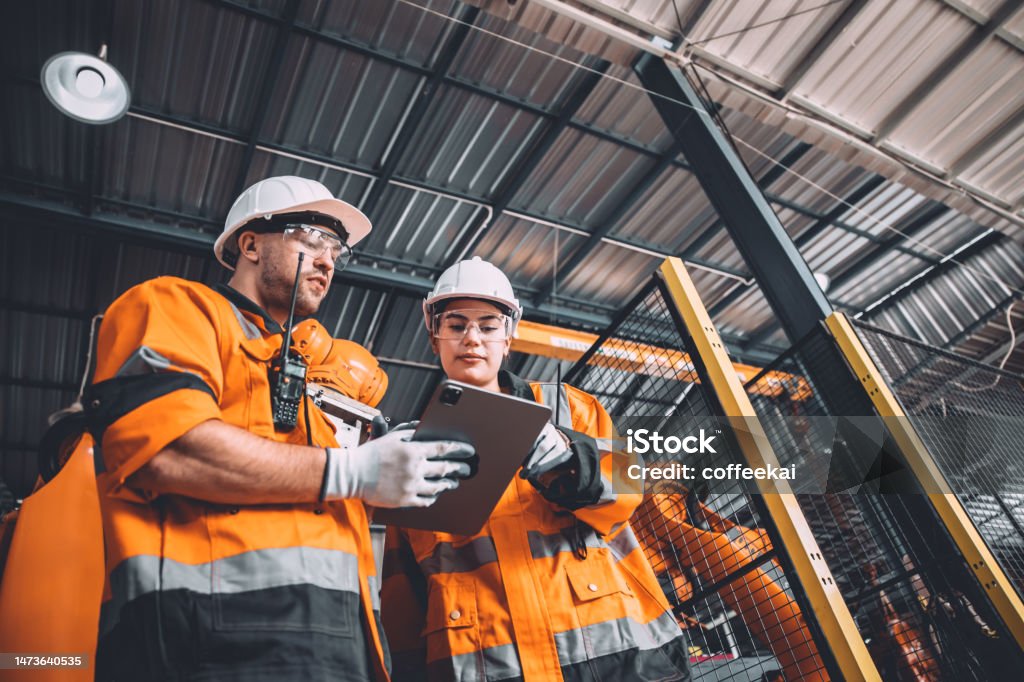 Workers holding helmets discuss GMG EnviroSafe safety compliance training in a warehouse setting