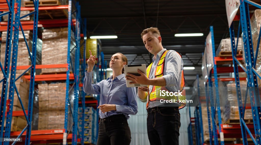 Workers holding helmets discuss GMG EnviroSafe safety compliance training in a warehouse setting
