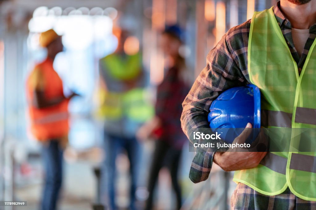Workers holding helmets discuss GMG EnviroSafe safety compliance training in a warehouse setting